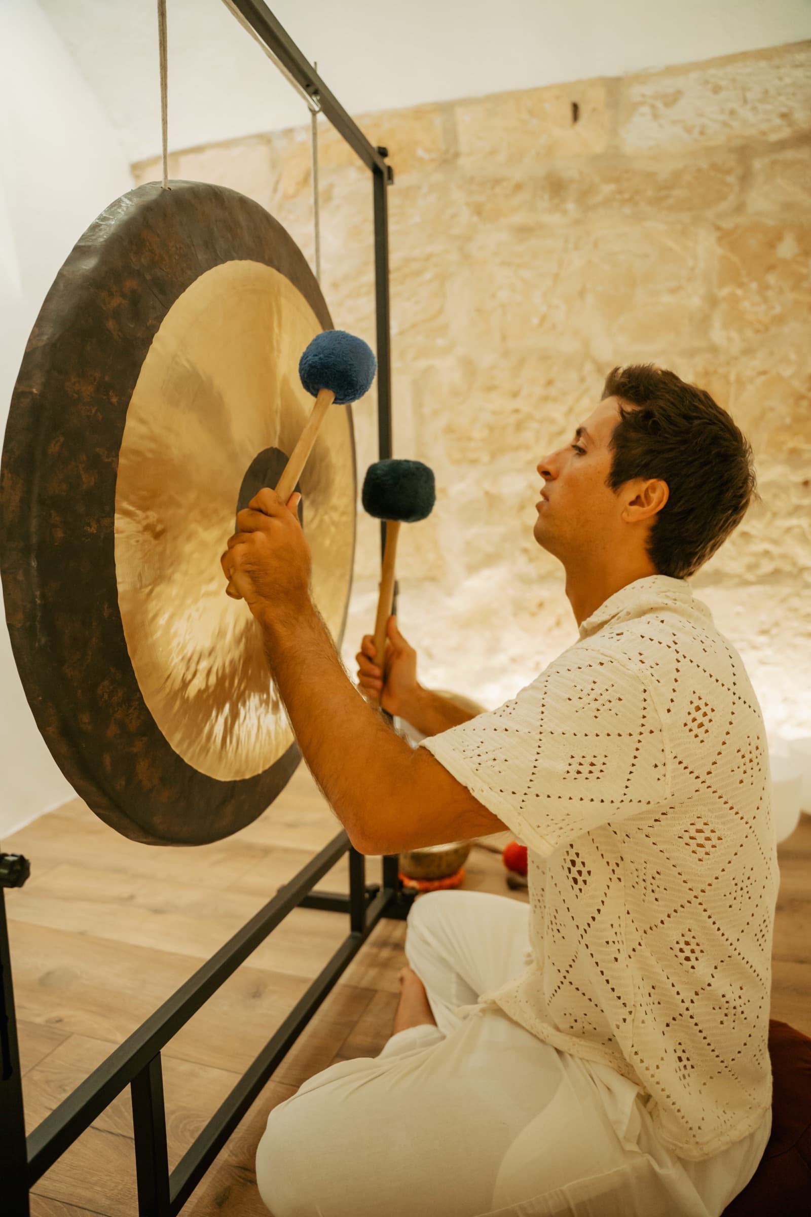 Facilitador tocando el gong en una sala de piedra