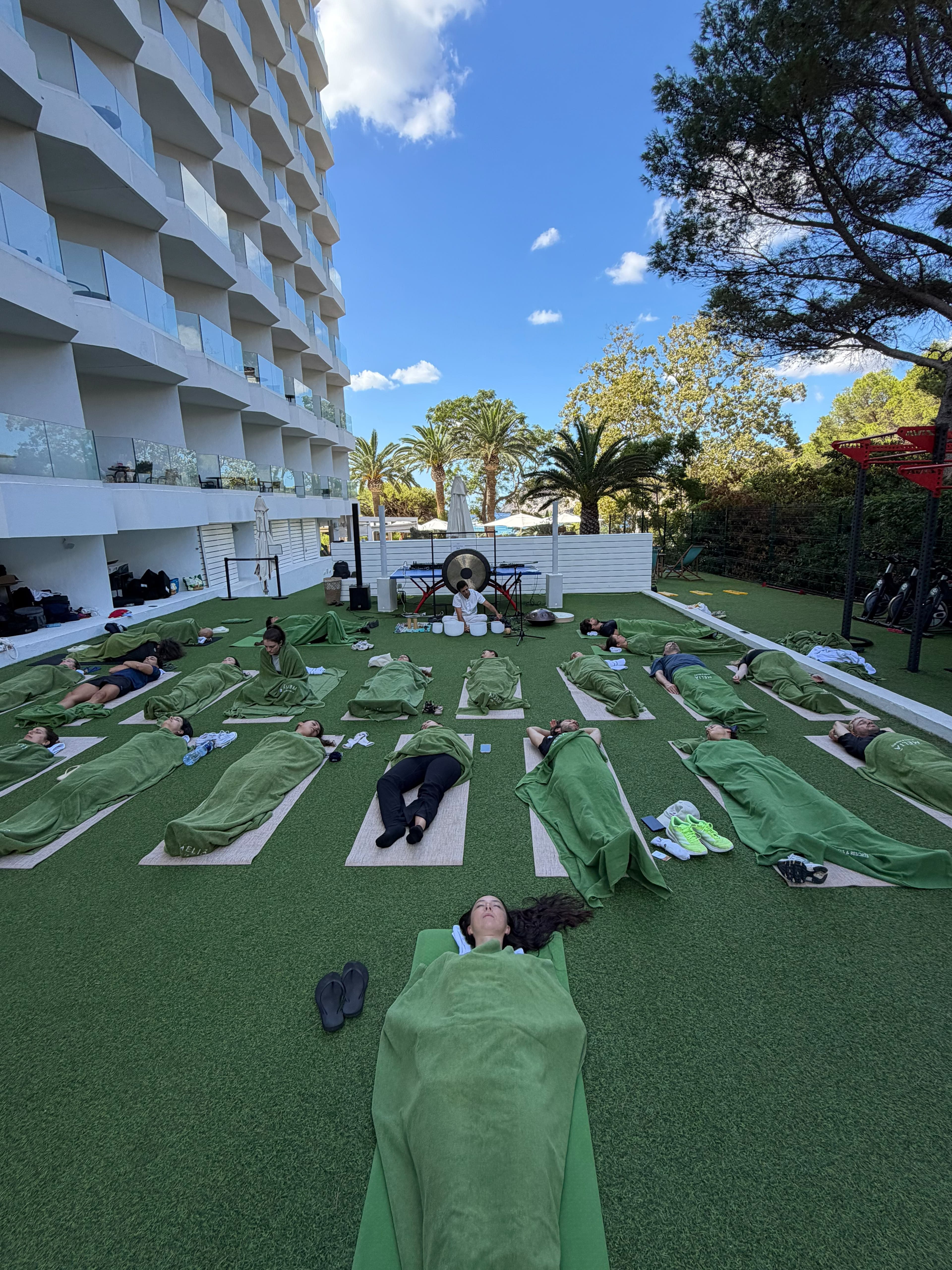 Huéspedes tumbados en el jardín de un hotel durante una meditación guiada