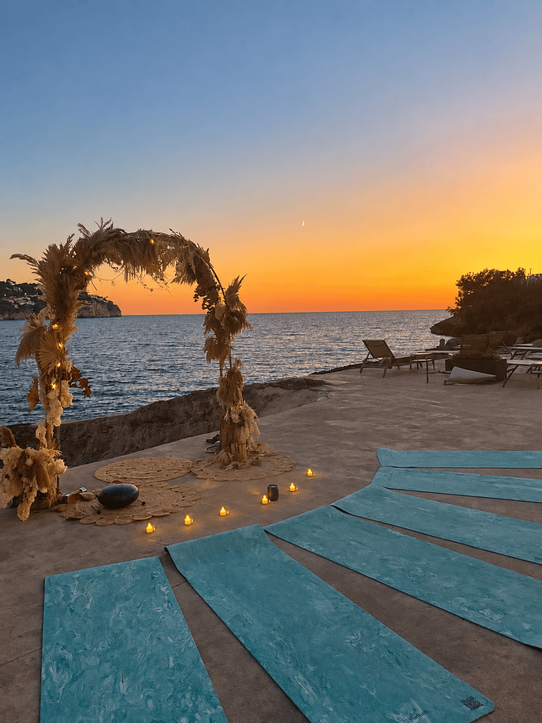Arco de flores y esterillas junto al mar al atardecer